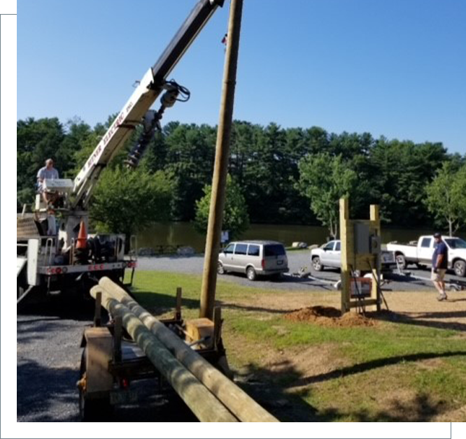 A crane is lifting logs on the side of a road.